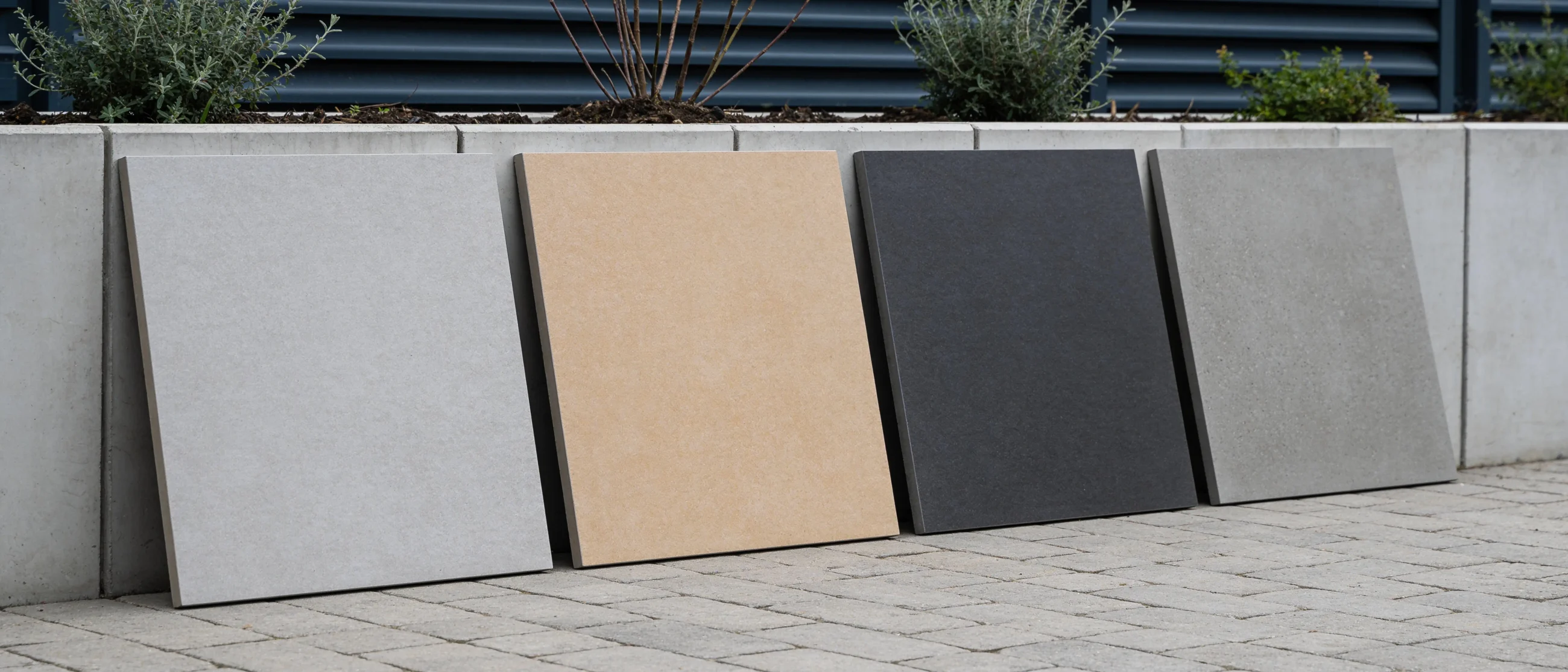 Großformatige Terrassenplatten in vier Farben an einer Gartenmauer