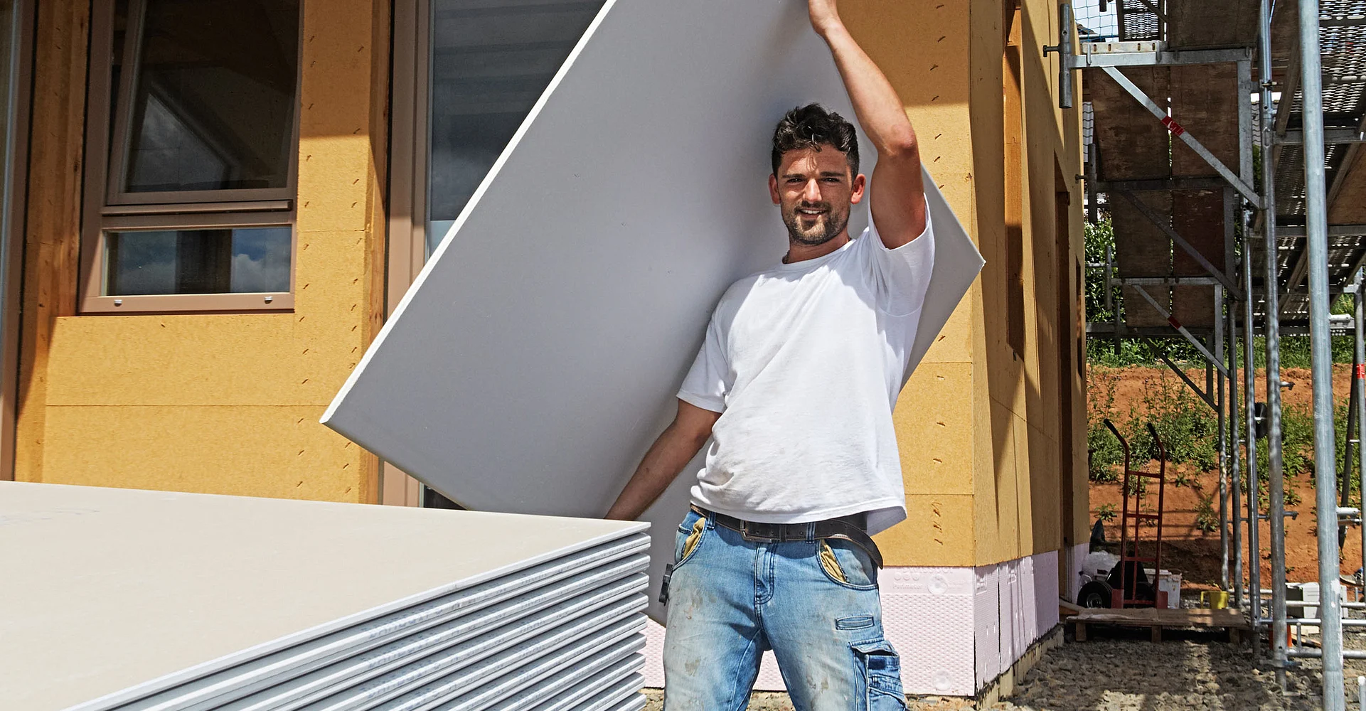 Handwerker trägt eine Platte zur Baustelle