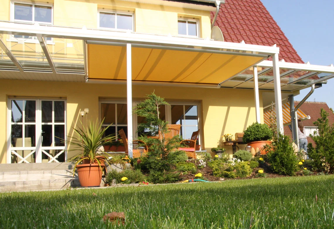 Terrassendach mit Markise an einem gelben Haus