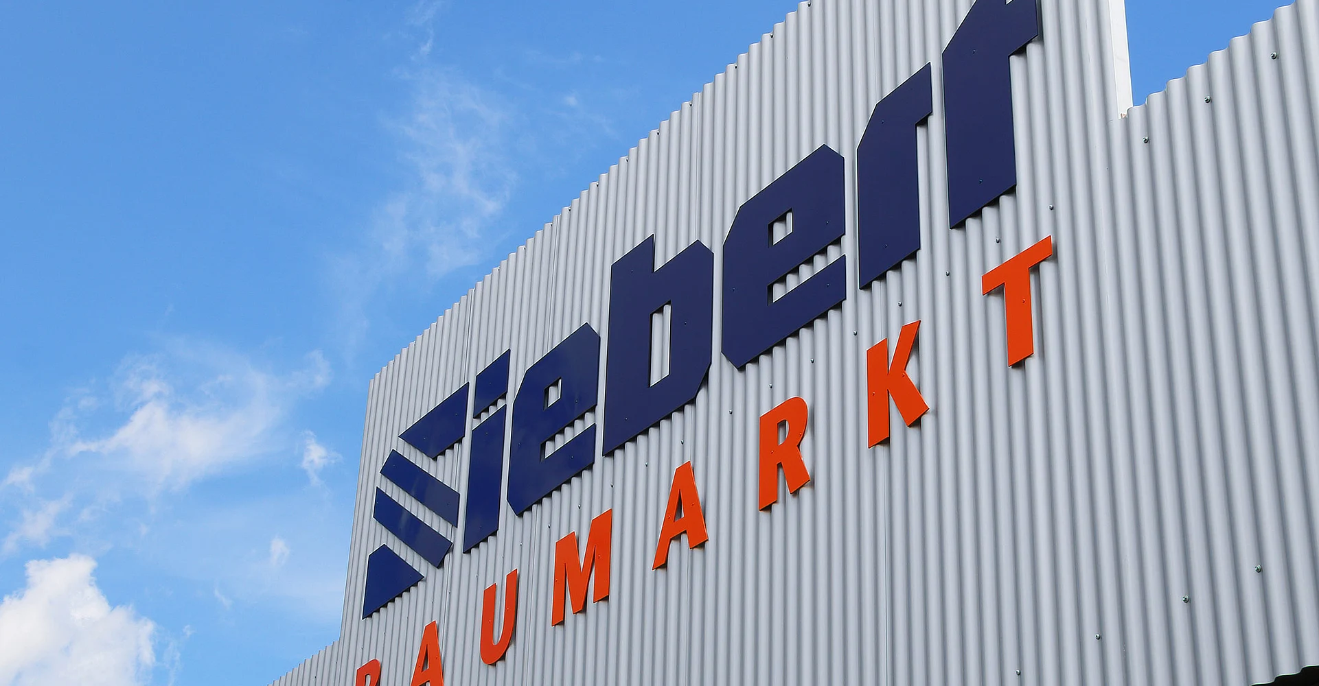 Fassade des Siebert Baumarkts mit großem Logo vor blauem Himmel