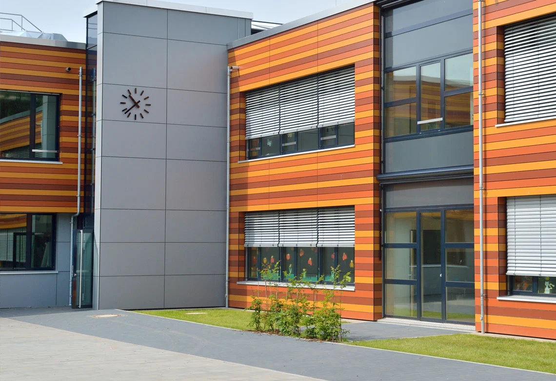 Schulgebäude mit orangefarbenen HPL-Fassadenstreifen