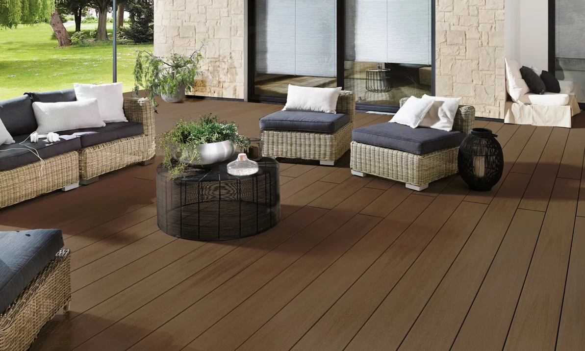 Rattan-Lounge mit Kissen auf einer Holzterrasse