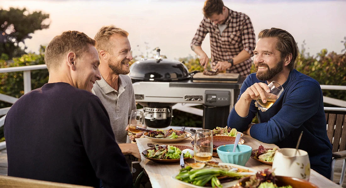 Freunde am gedeckten Tisch neben dem Grill