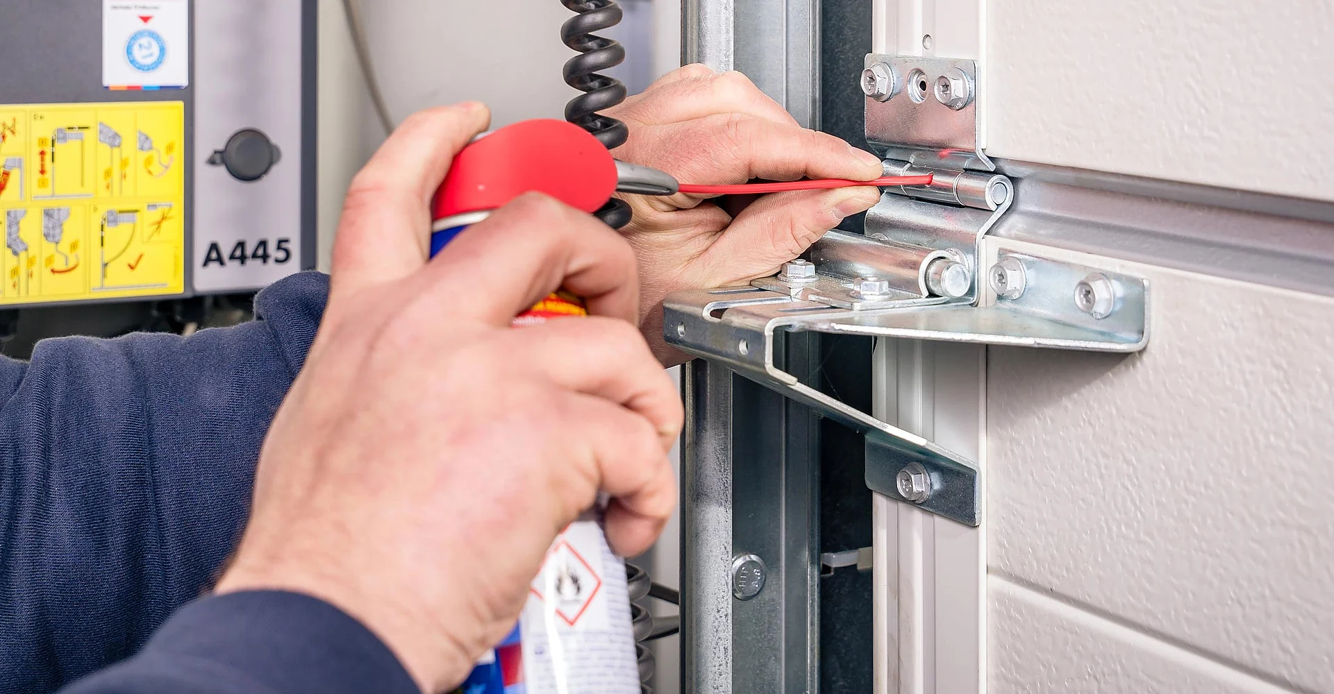 Service-Monteur ölt die Laufschiene eines Garagentors